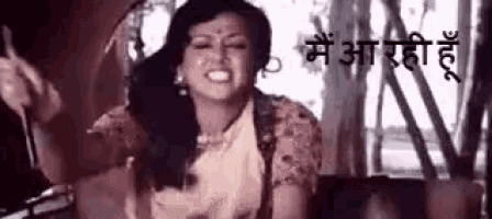a woman in a sari is sitting in front of a window and making a funny face in a black and white photo .