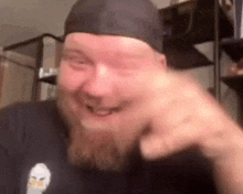 a man with a beard is wearing a beanie and making a funny face .