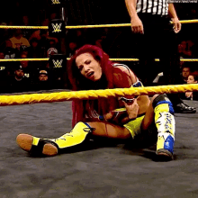 a woman is laying on the ground in a wrestling ring