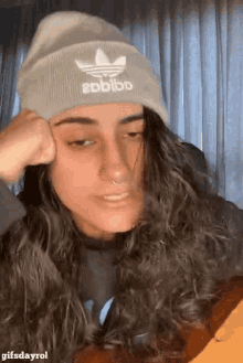 a woman wearing a beanie with the word adidas on it is sitting at a table .