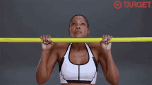 a woman in a sports bra is doing a pull up on a yellow bar