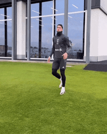 a man walking on a grassy field with a mercedes logo on his shirt