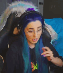 a woman with purple hair and glasses is wearing headphones and a furry jacket .