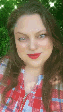 a woman wearing a plaid shirt and red lipstick smiles
