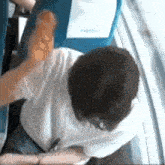 a man in a white shirt is sitting in a blue chair with his arm outstretched ..