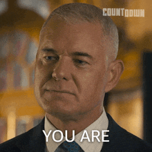 a man in a suit and tie says " you are " in front of a countdown logo