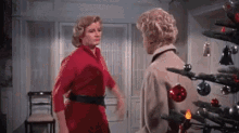 two women are standing next to each other in front of a christmas tree in a room .