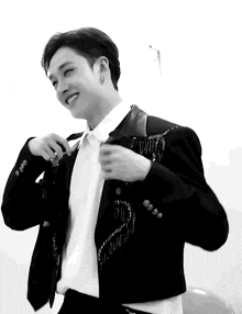 a black and white photo of a young man wearing a suit and tie .