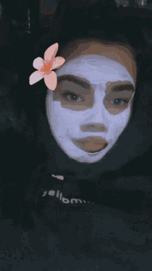 a woman wearing a black hoodie has a purple face mask on