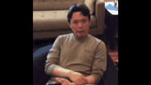 a man is sitting on a bean bag chair in front of a couch holding a cell phone .