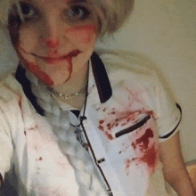 a woman with blood on her face is wearing a white shirt with a black collar