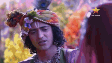 a man wearing a turban with a peacock feather on top of it and a star on the bottom right