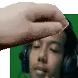 a hand is touching a man 's forehead while he is wearing headphones .