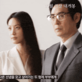 a man in a suit and tie stands next to a woman with glasses