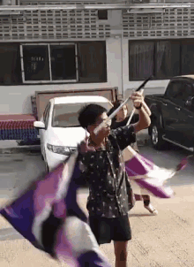 a man is holding a purple and white flag in front of a white truck