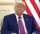 donald trump is sitting in front of an american flag with his eyes closed .