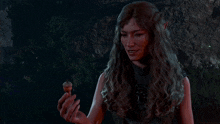 a woman is holding an acorn in her hand