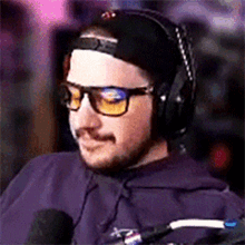 a man wearing headphones and glasses sitting in front of a microphone .