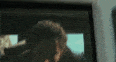 a close up of a man 's face looking out of a car window