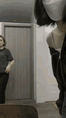 a woman wearing a mask is standing next to a man in a striped shirt