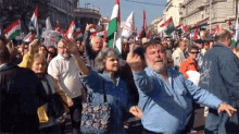 a man in a blue shirt is giving the middle finger in a crowd