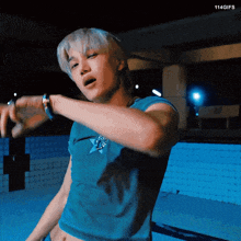 a man in a blue crop top is dancing in front of a pool with 114gifs written on the bottom