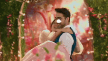 a man is carrying a woman in his arms in a pink dress .