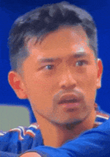 a man with a beard is wearing a blue shirt and looking at the camera