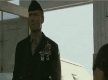 a man in a military uniform is standing in front of a window in a room .
