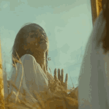 a woman is looking at herself in a mirror while standing in a field of tall grass