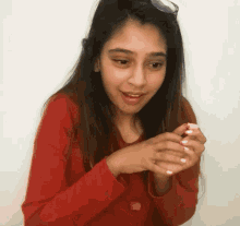 a woman wearing a red shirt and sunglasses is holding something in her hands