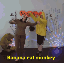 two people in banana costumes are dancing in front of a sign that says " banana eat monkey "