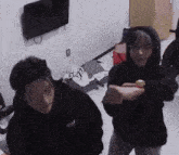 two people are standing next to each other in a room .