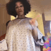 a woman in a hospital gown is standing in a room holding a toy .