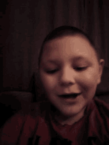 a close up of a child 's face with a red shirt that has the letter t on it