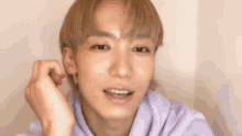 a close up of a young man wearing a purple hoodie making a funny face .