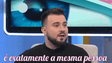 a man with a beard is sitting in front of a television with the words " e exatamente a mesma pessoa " above him