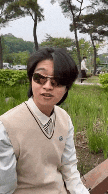 a man wearing sunglasses and a vest is sitting on a bench