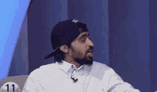 a man wearing a hat and a white shirt is sitting in front of a number 11