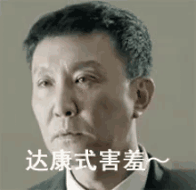 a man in a suit and tie is making a funny face with chinese writing on his face .