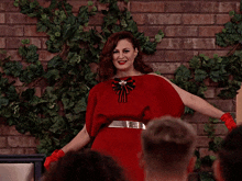 a woman in a red dress is standing in front of a crowd