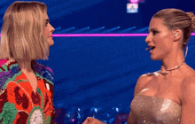 two women are standing next to each other on a stage with a blue background