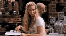 a woman sitting at a table reading a magazine