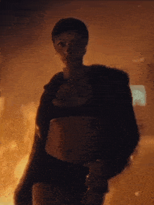 a woman is standing in front of a fire in the dark .