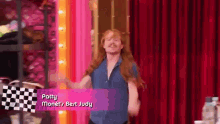 a man with long red hair and a mustache is dancing on a red curtain .
