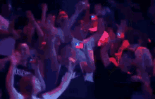 a crowd of people are dancing in a dark room with the word moschino visible