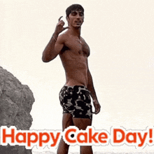 a shirtless man in swim trunks is standing on a beach with the words happy cake day .