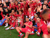 a group of soccer players are posing for a picture with the trophy