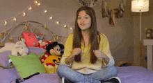a girl sitting on a bed with stuffed animals