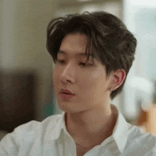 a close up of a young man wearing a white shirt and earring .